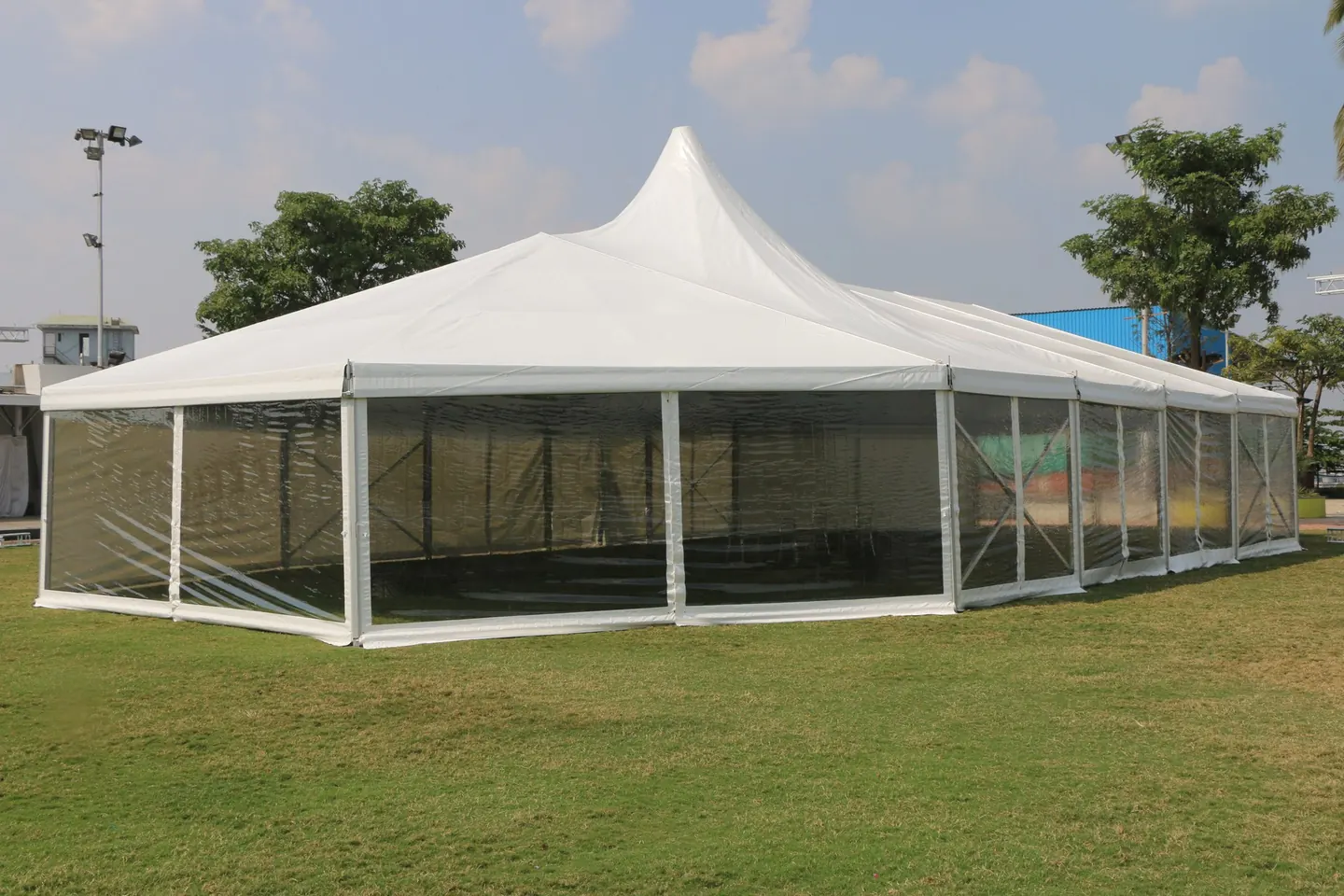 A clear-walled pagoda tent pitched on grass, with a white peaked roof